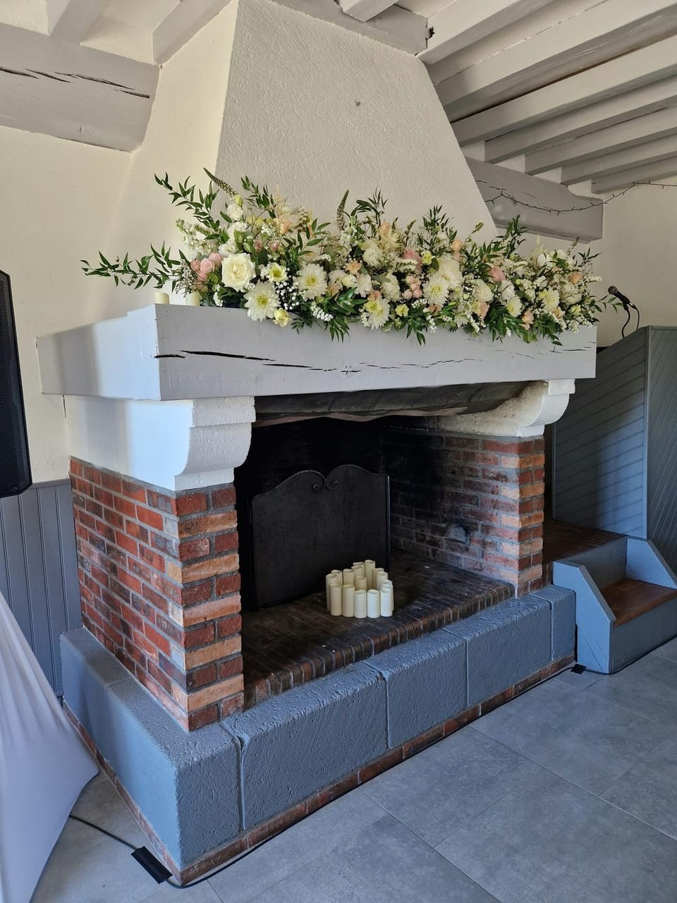 La cheminée de brique habillée d’une longue guirlande de fleurs blanches et de bougies