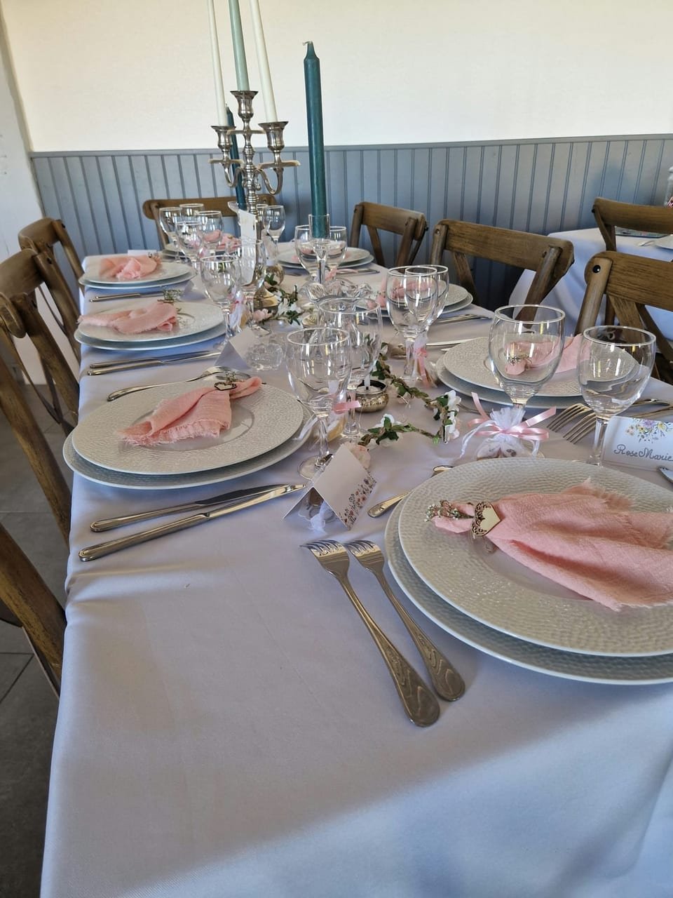 Table dressée en rose poudré, chaises bistrot en bois et bougies vertes