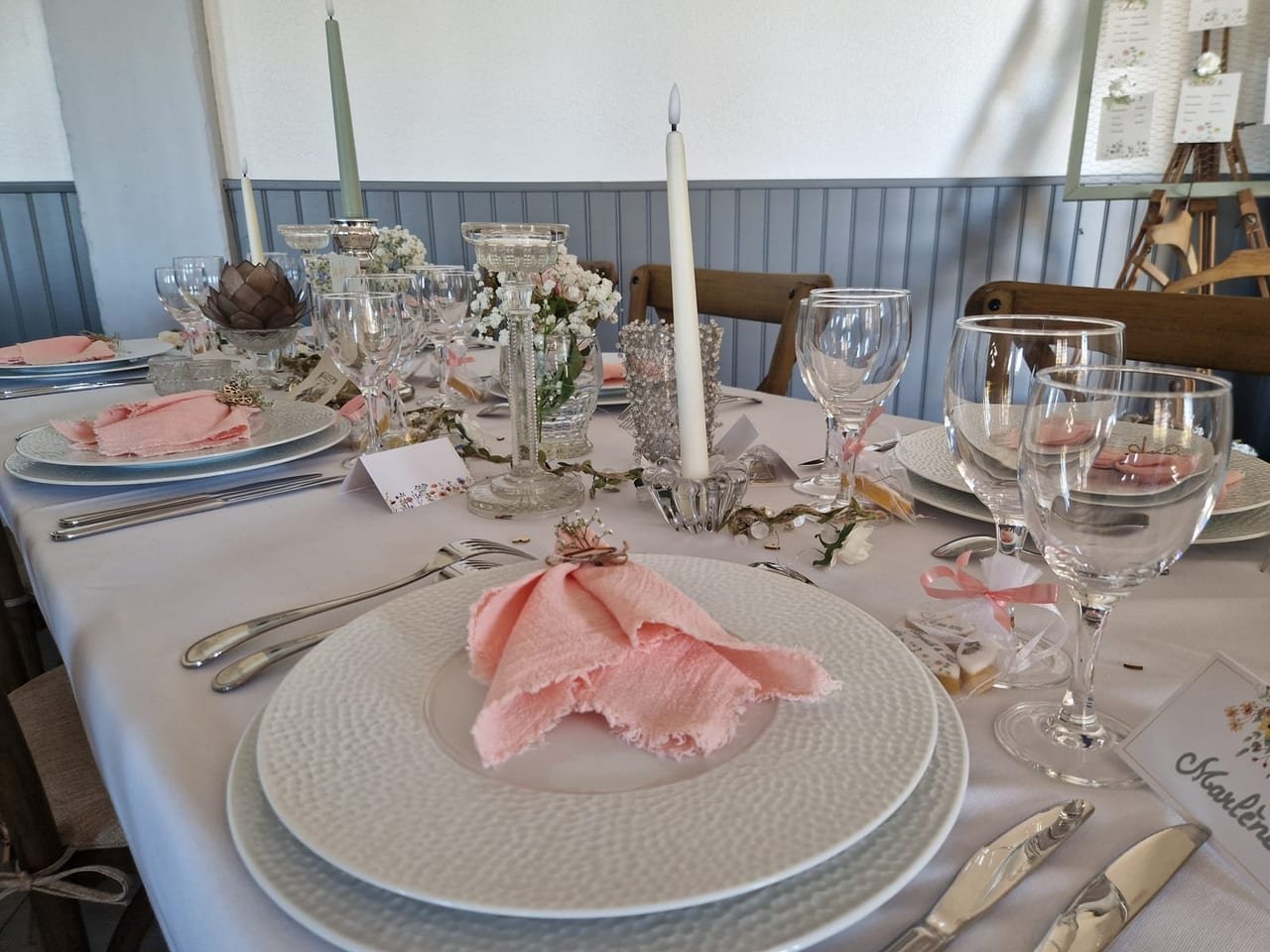 Couvert dressé : assiettes texturées, serviette rose poudré et candélabre d’argent