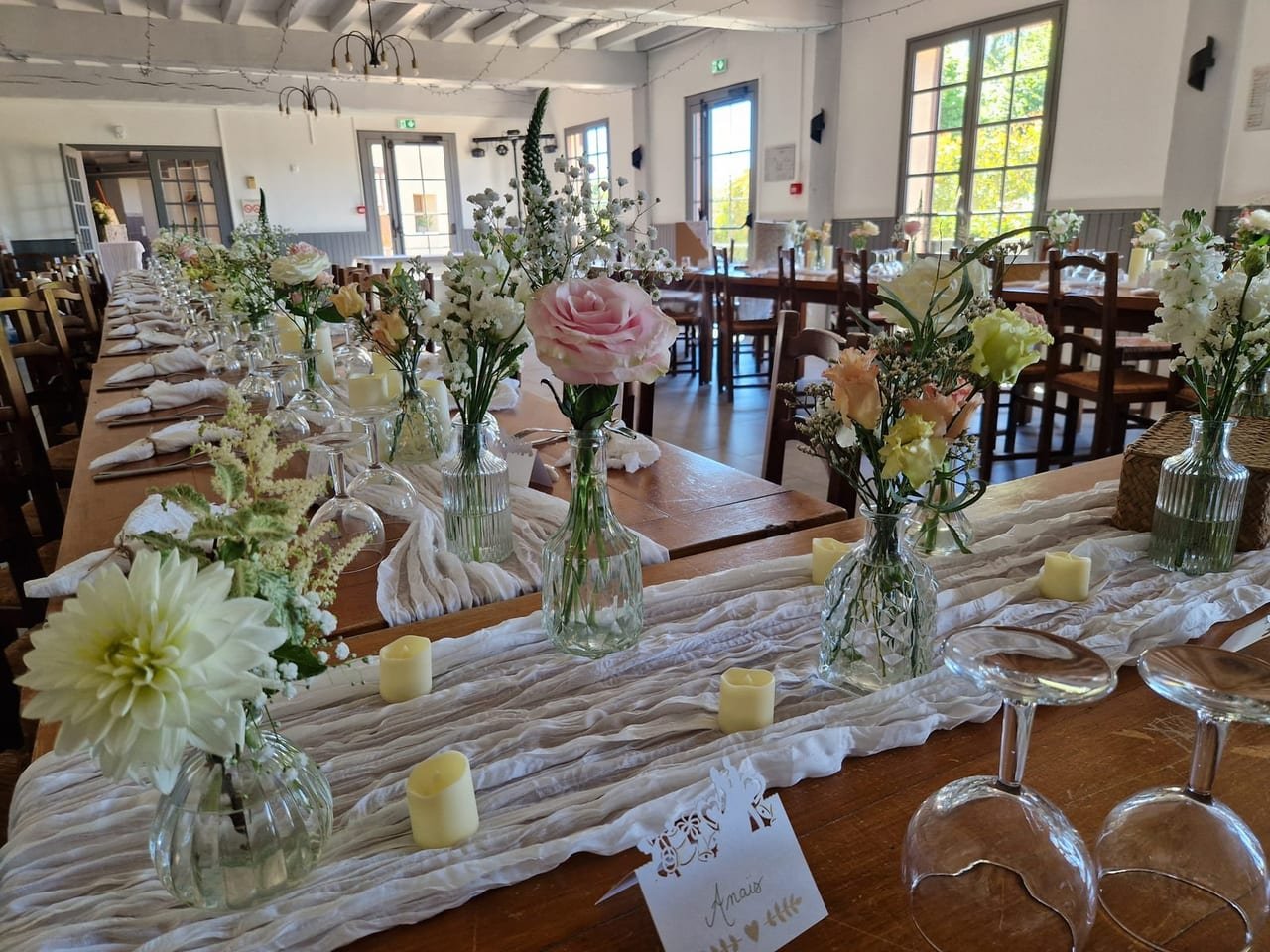 Tablée en bois brut, chemin de gaze froissée, soliflores et bougies
