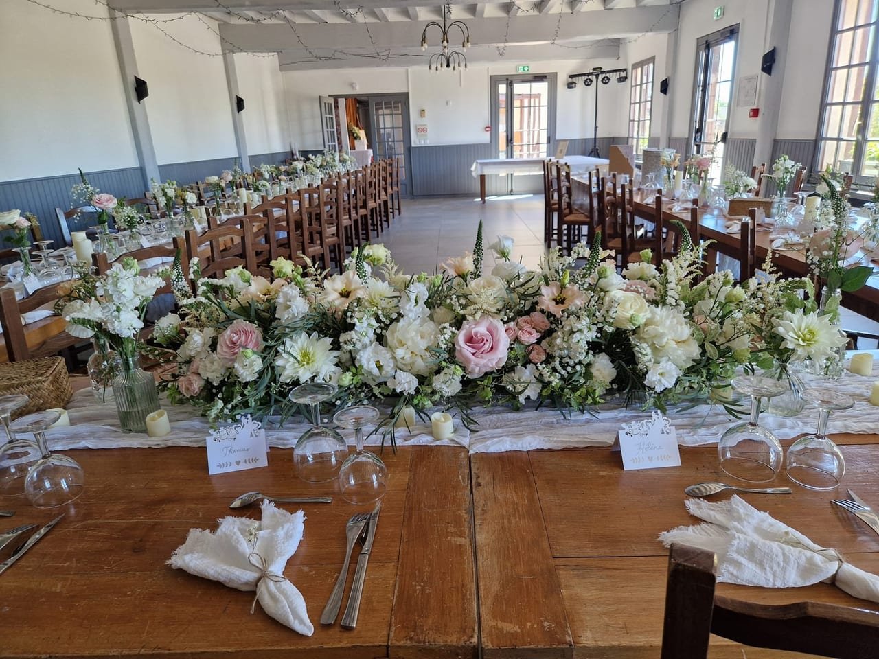 Longues tables de bois brut et grande composition de roses, dahlias et pivoines blanches